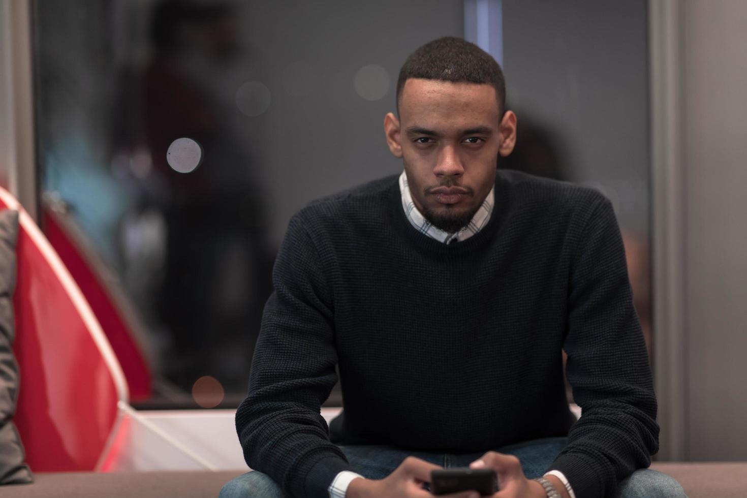 Young African American work in coworking space using smartphone analyzing online market trends, focused man worker reading financial news or browsing internet on phone. Technology concept photo