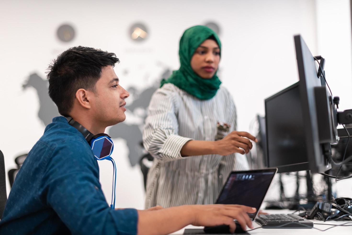 mujer árabe del equipo de negocios de inicio multiétnico que usa un hiyab en una reunión en una moderna oficina de diseño abierto interior lluvia de ideas, trabajando en una computadora portátil y de escritorio. enfoque selectivo foto