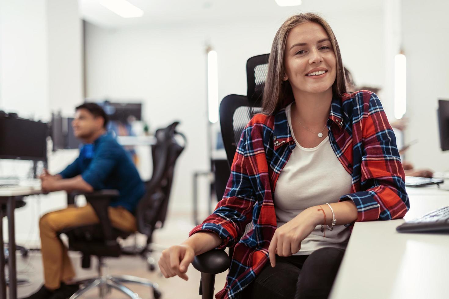 Casual business woman working on desktop computer in modern open plan startup office interior. Selective focus photo