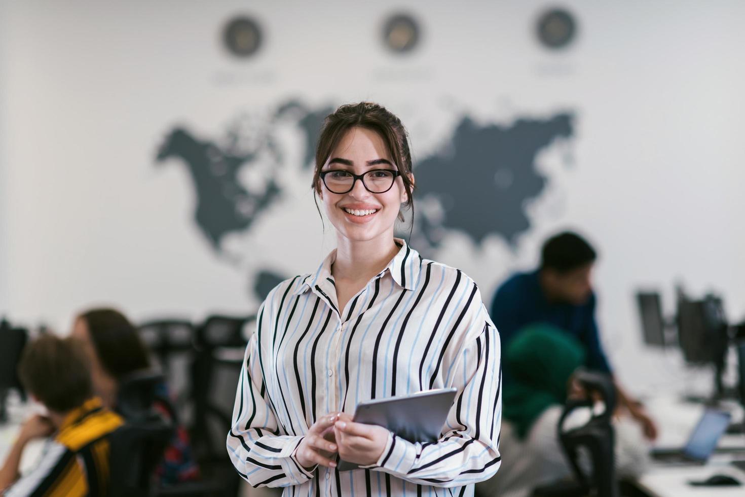 Portrait of businesswoman in casual clothes holding tablet computer at modern startup open plan office interior. Selective focus photo
