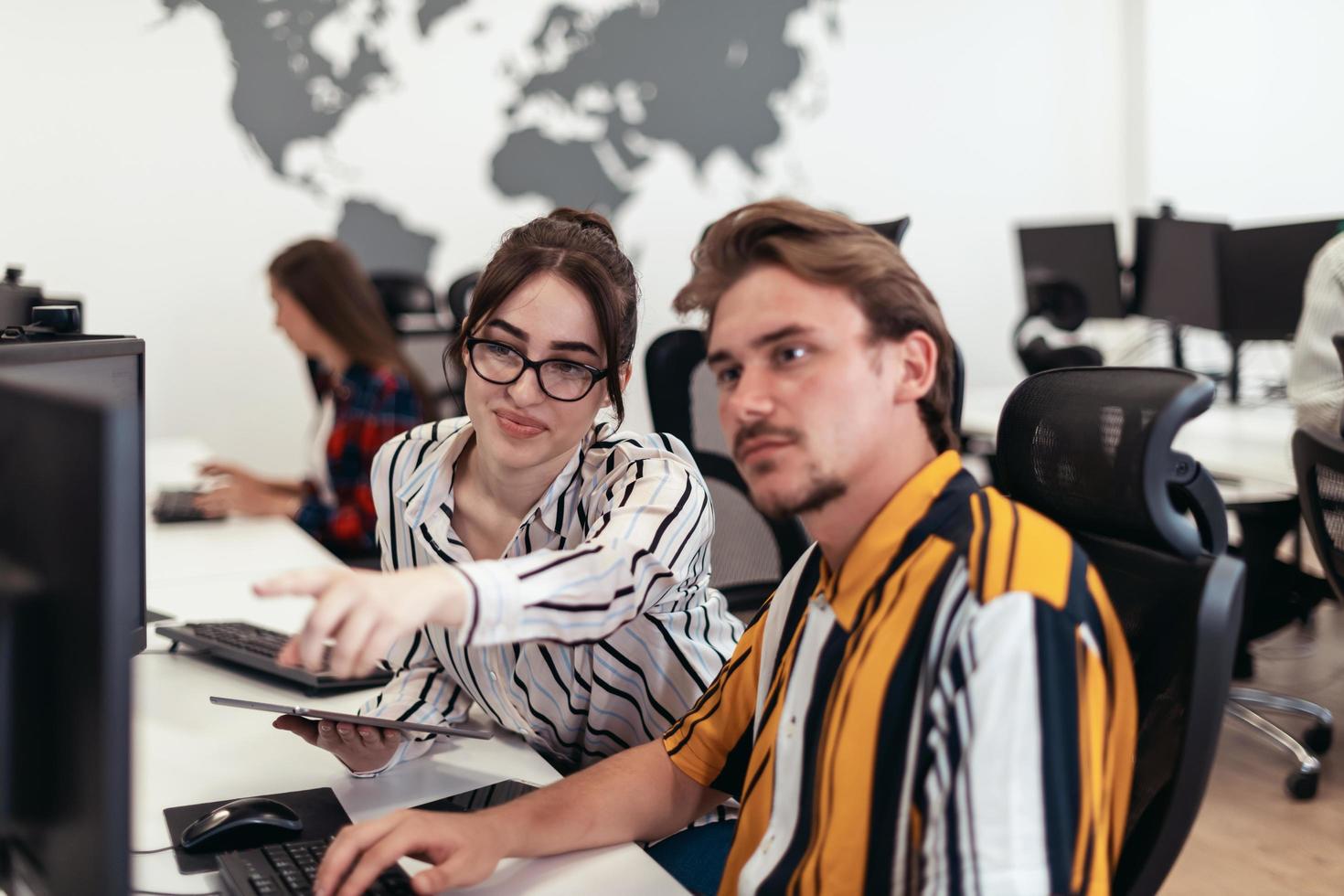 Business couple working together on project using tablet and desktop computer at modern open plan startup office. Selective focus photo