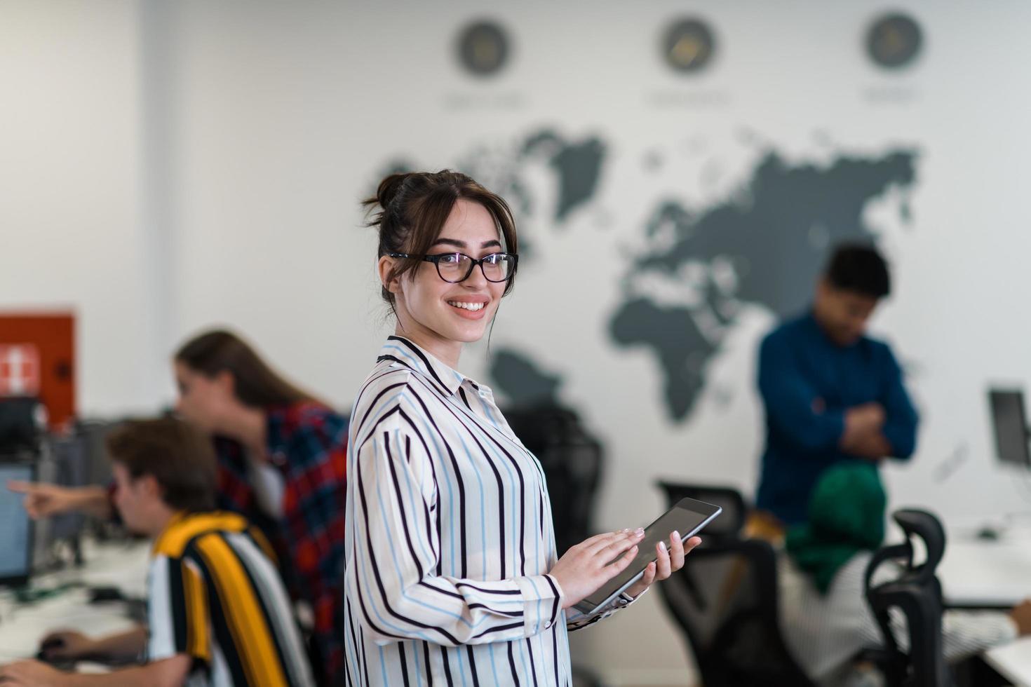 Portrait of businesswoman in casual clothes holding tablet computer at modern startup open plan office interior. Selective focus photo