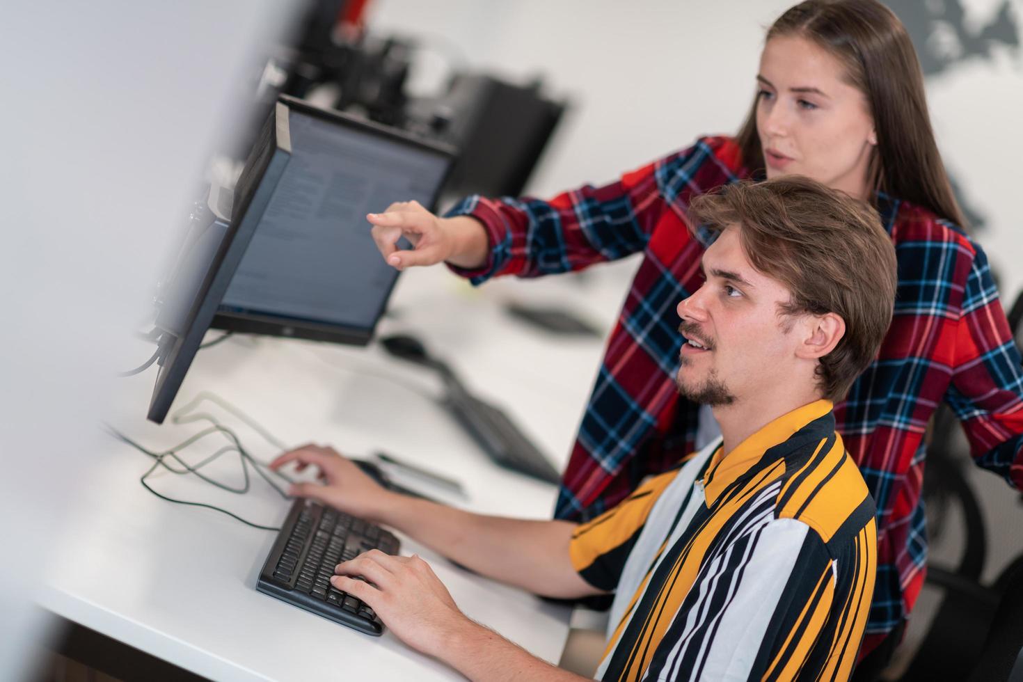 Business couple working together on project using tablet and desktop computer at modern open plan startup office. Selective focus photo