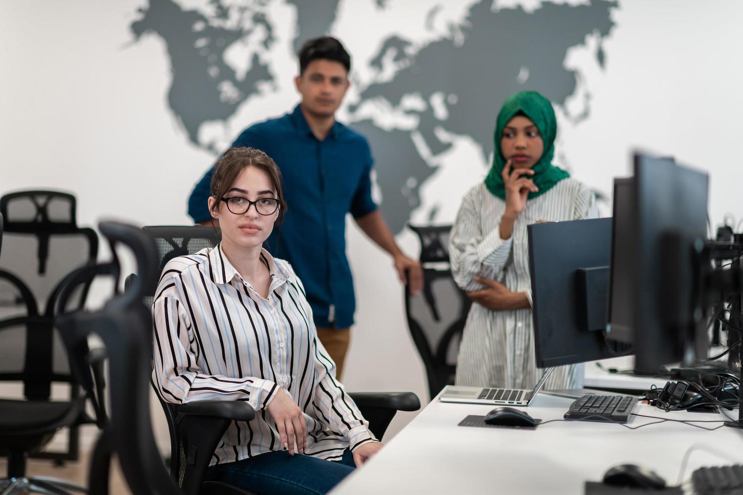 Multiethnic startup business team Arabian woman wearing a hijab on meeting in modern open plan office interior brainstorming, working on laptop and desktop computer. Selective focus photo