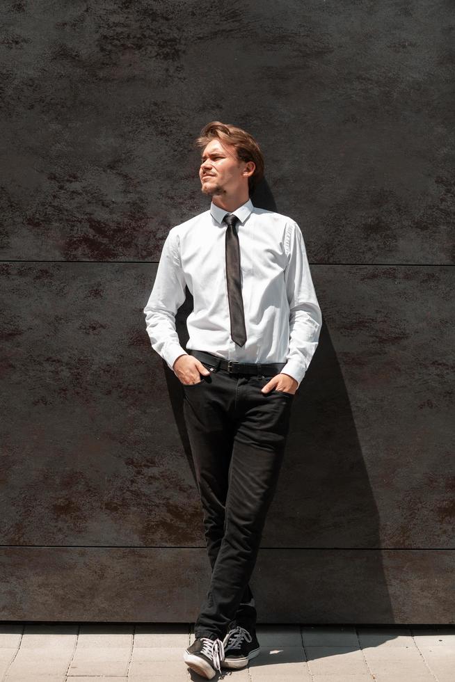 de un nuevo hombre de negocios con una camisa blanca y una corbata negra parado frente una pared gris afuera 12534552 Foto de en Vecteezy