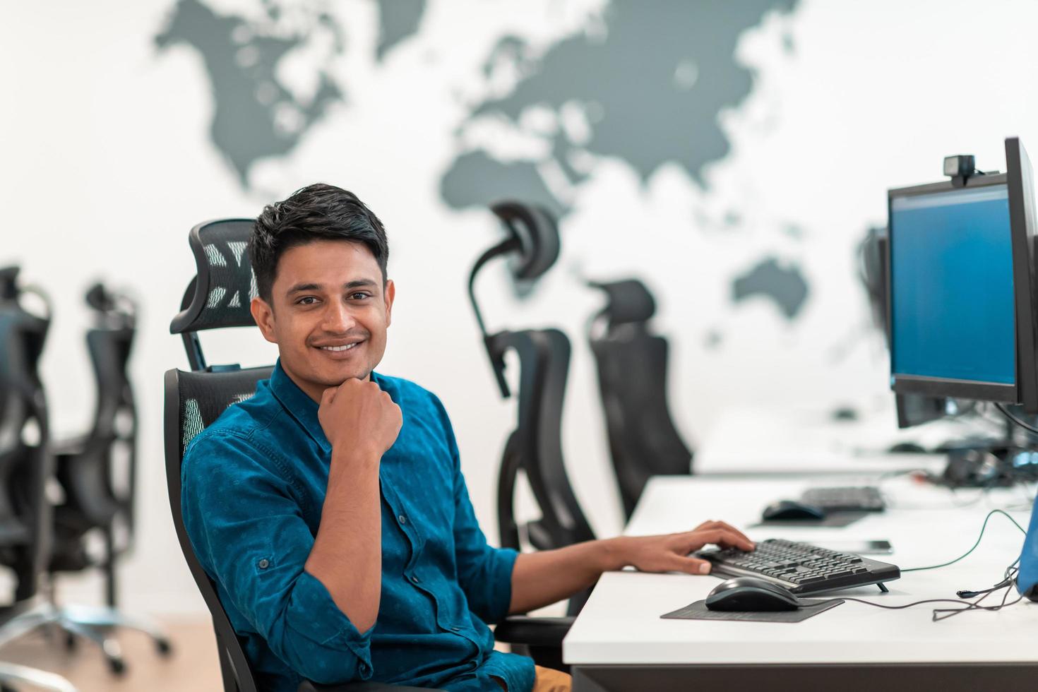 Casual business man working on desktop computer in modern open plan startup office interior. Selective focus photo