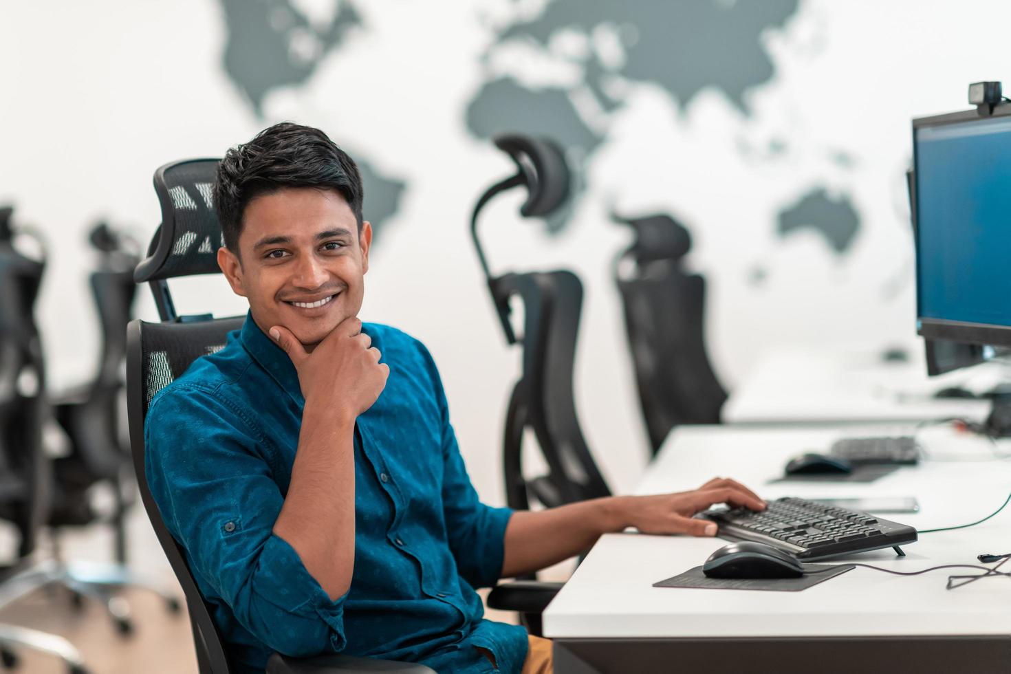 Casual business man working on desktop computer in modern open plan startup office interior. Selective focus photo