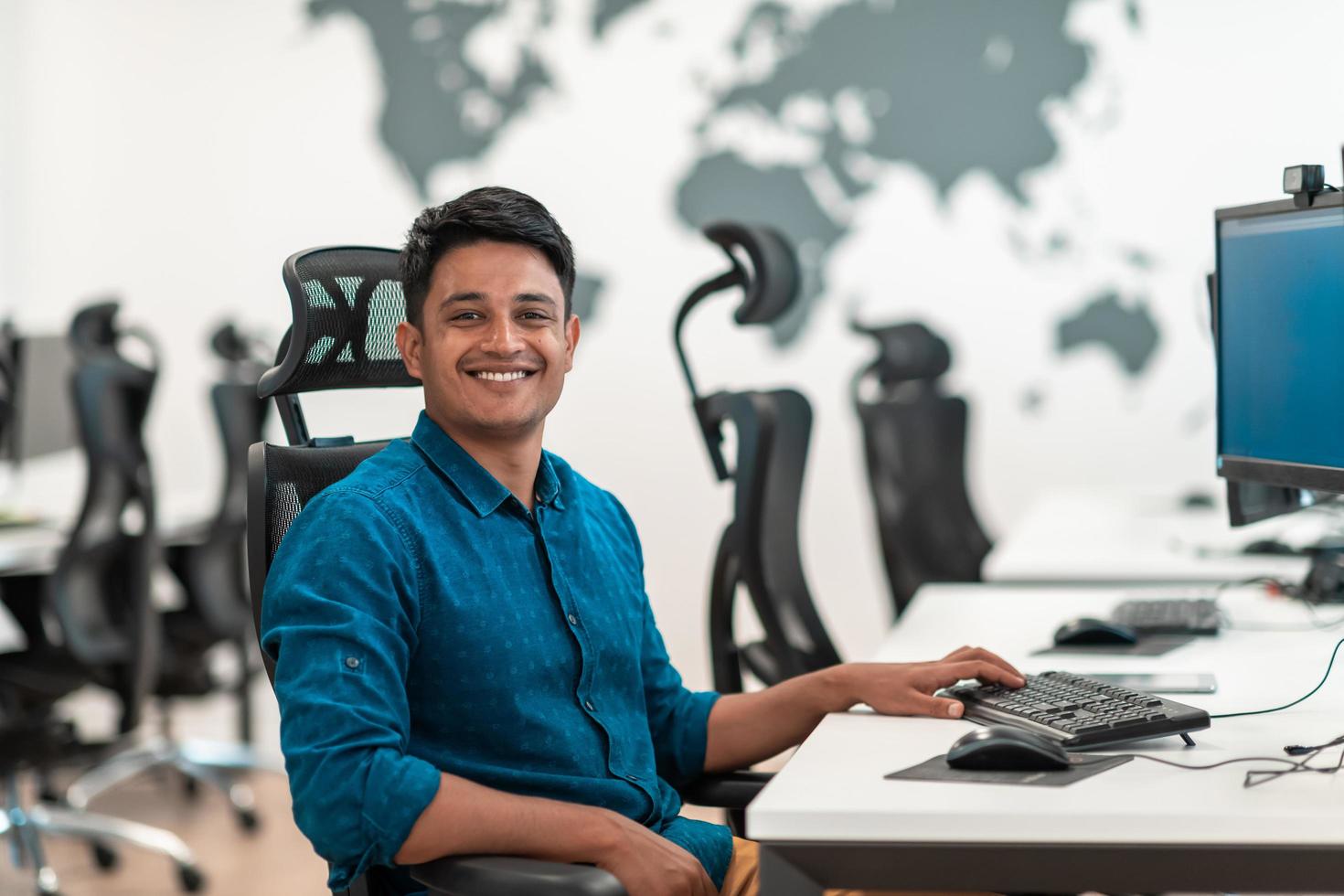 Casual business man working on desktop computer in modern open plan startup office interior. Selective focus photo