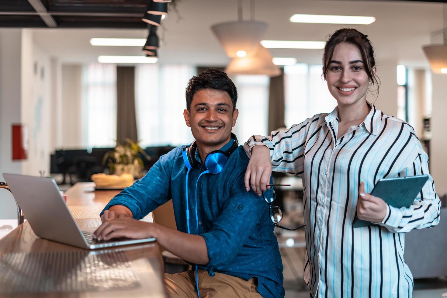 Multiethnic business people man with a female colleague working together on tablet and laptop computer in relaxation area of modern startup office photo