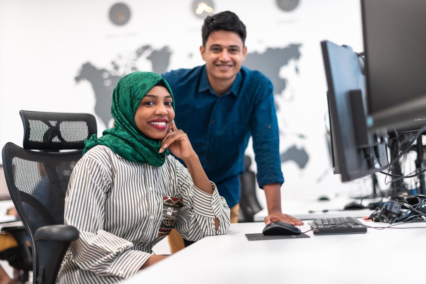 Multiethnic startup business team woman wearing a hijab on meeting in modern open plan office interior brainstorming, working on laptop and desktop computer. Selective focus photo