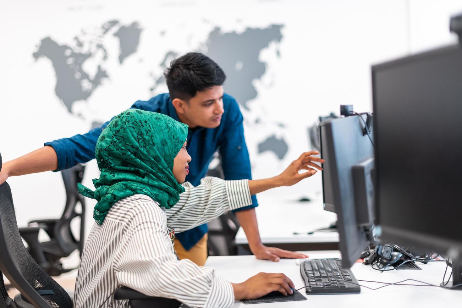 Multiethnic startup business team Arabian woman wearing a hijab on meeting in modern open plan office interior brainstorming, working on laptop and desktop computer. Selective focus photo