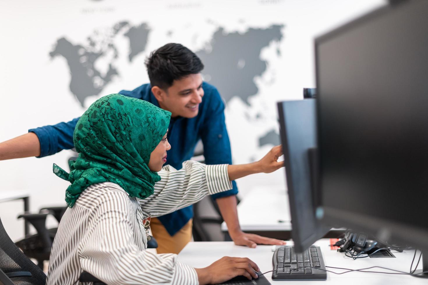 Multiethnic startup business team woman wearing a hijab on meeting in modern open plan office interior brainstorming, working on laptop and desktop computer. Selective focus photo