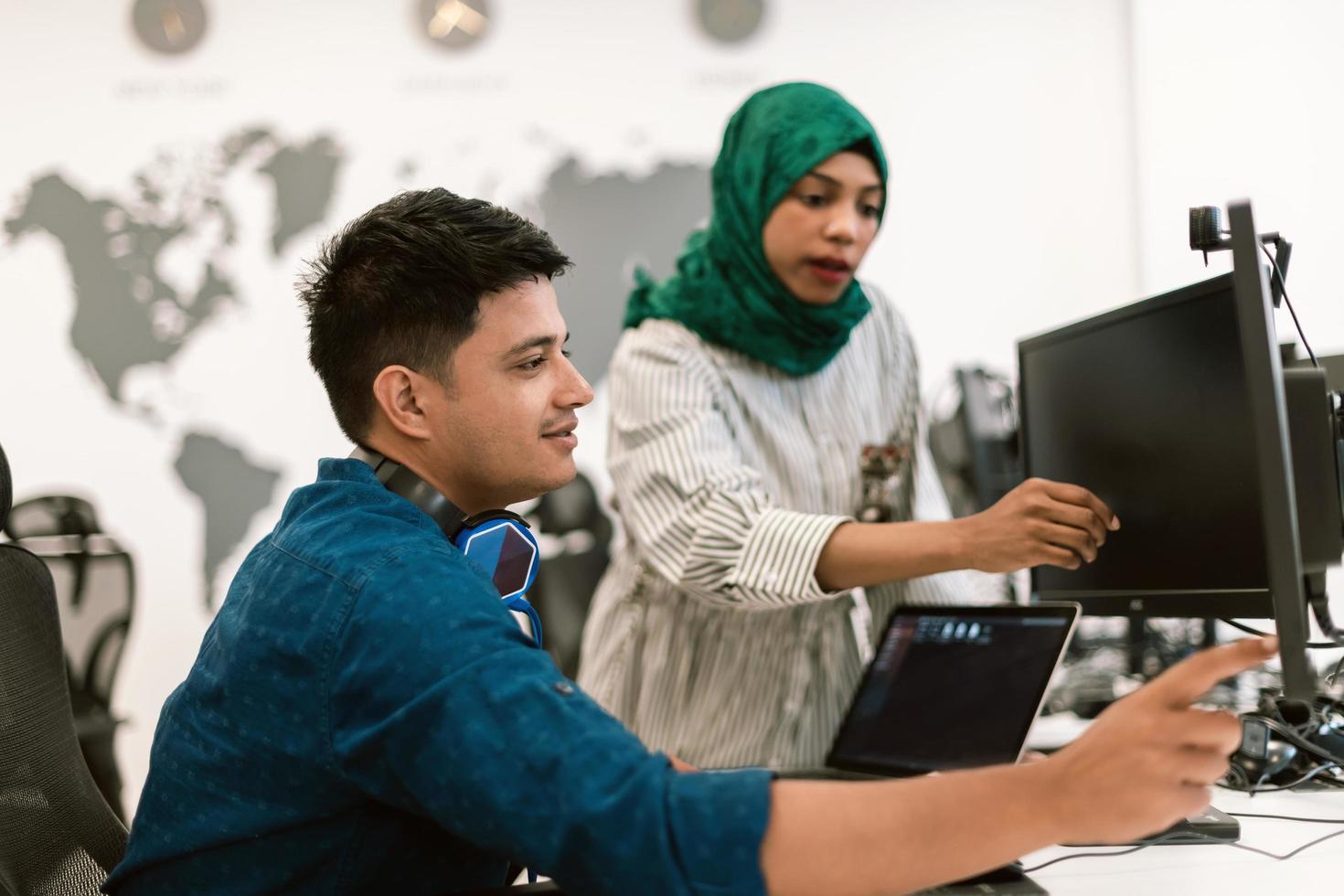 Multiethnic startup business team woman wearing a hijab on meeting in modern open plan office interior brainstorming, working on laptop and desktop computer. Selective focus photo