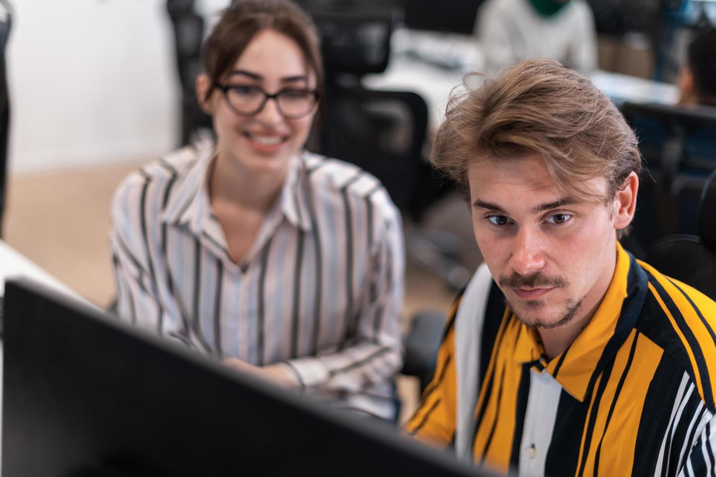 Business couple working together on project using tablet and desktop computer at modern open plan startup office. Selective focus photo