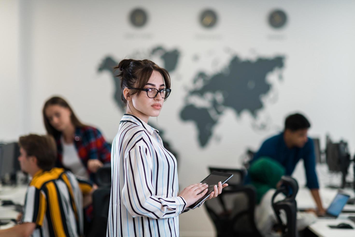Portrait of businesswoman in casual clothes holding tablet computer at modern startup open plan office interior. Selective focus photo