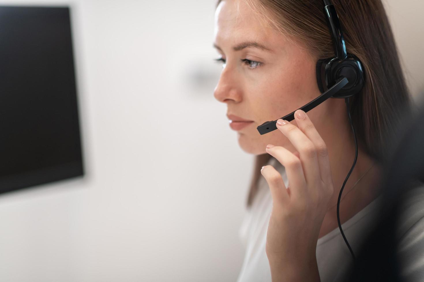 Helpline female operator with headphones in call centre.Business woman with headsets working in a call center. Selective focus photo