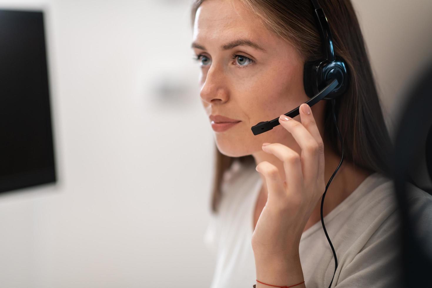 Helpline female operator with headphones in call centre.Business woman with headsets working in a call center. Selective focus photo