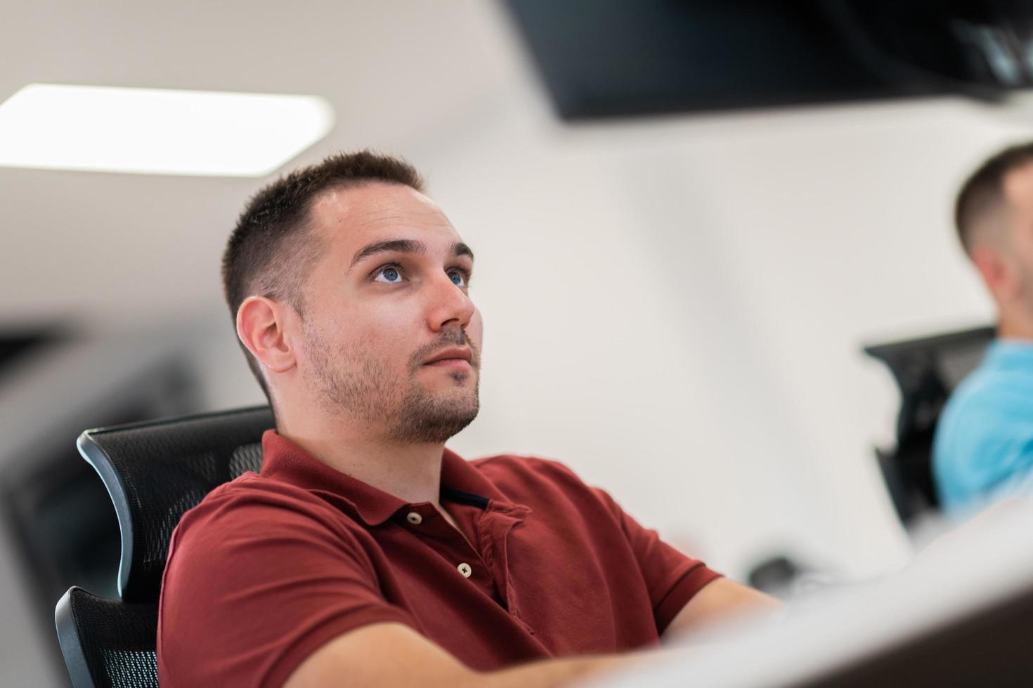 Casual business man working on desktop computer in modern open plan startup office interior. Selective focus photo