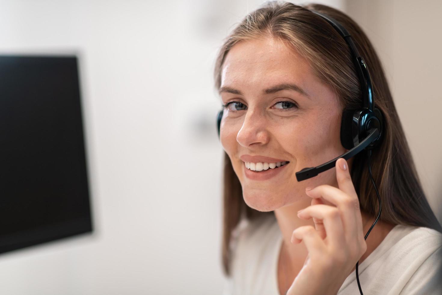 operadora de la línea de ayuda con auriculares en el centro de llamadas. mujer de negocios con auriculares trabajando en un centro de llamadas. enfoque selectivo foto