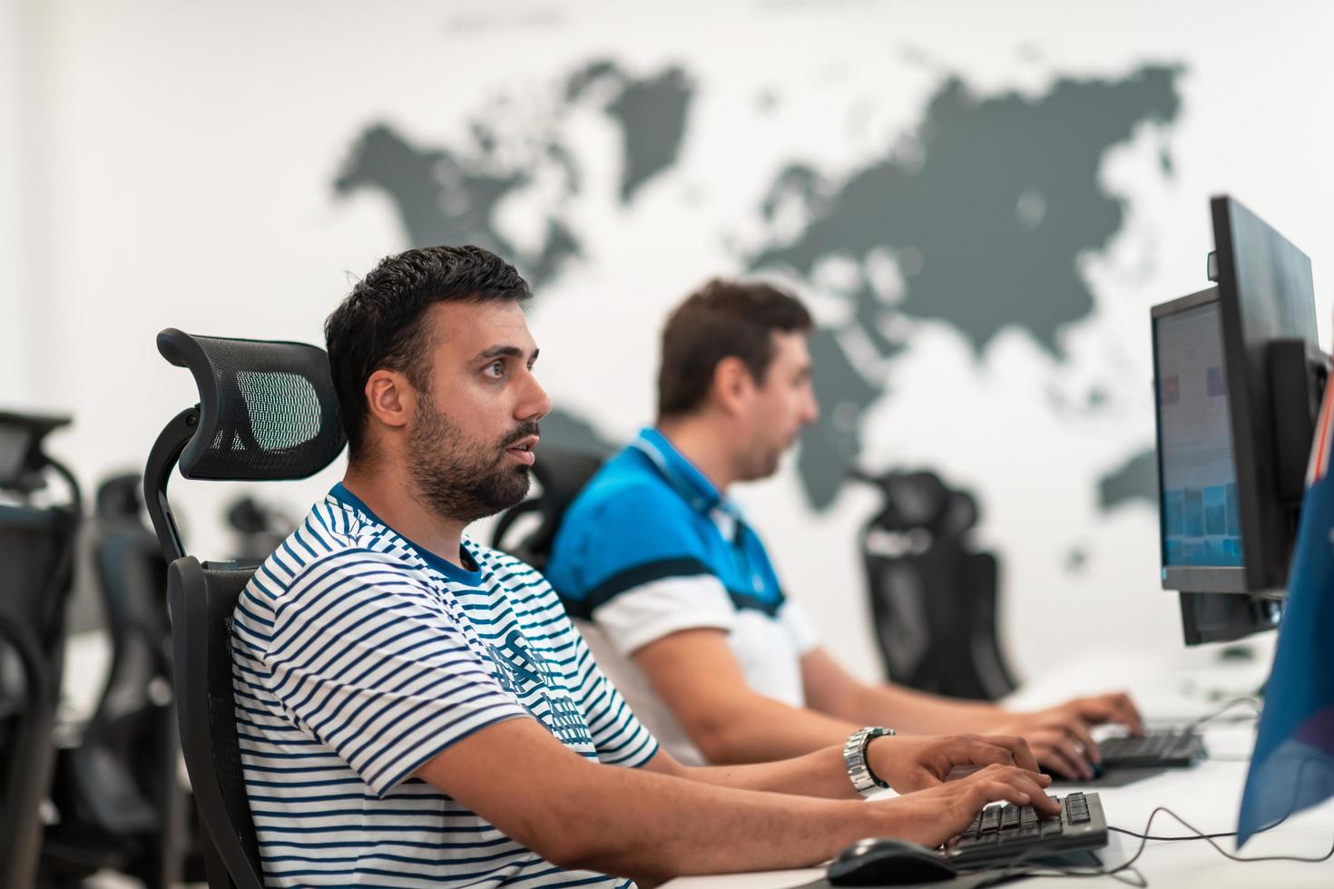 Group of Casual business man working on desktop computer in modern open plan startup office interior. Selective focus photo