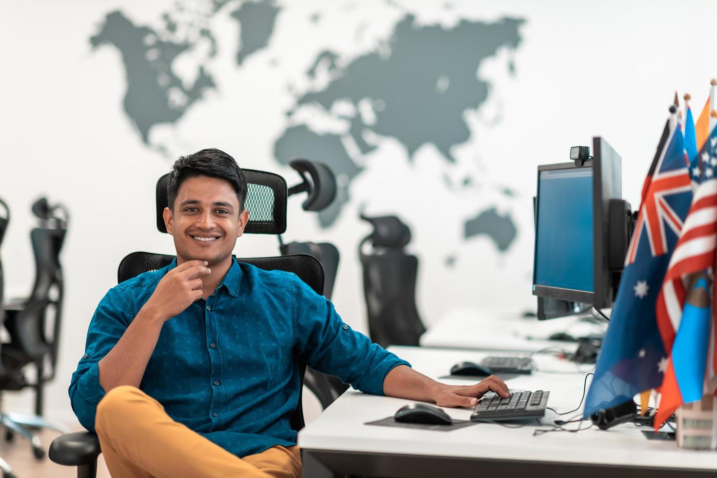 Casual business man working on desktop computer in modern open plan startup office interior. Selective focus photo