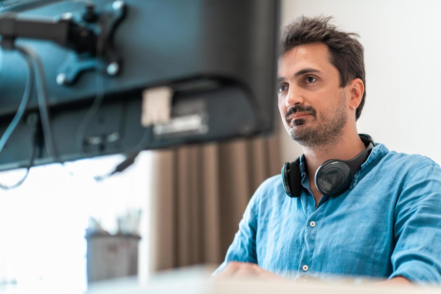 Casual man working on desktop computer in modern open plan startup office interior. Selective focus photo