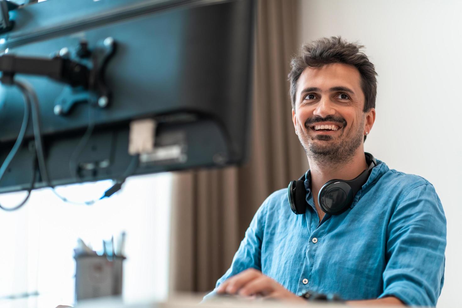 Casual man working on desktop computer in modern open plan startup office interior. Selective focus photo