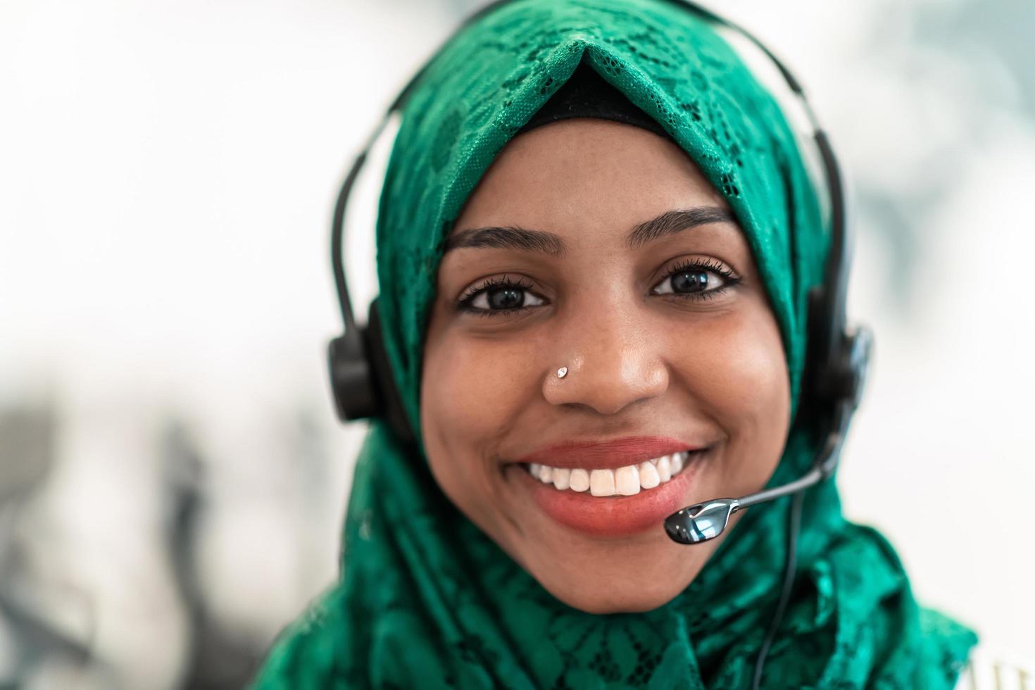 Muslim female with green hijab scarf customer representative business woman with phone headset helping and supporting online with customer in modern call centre photo