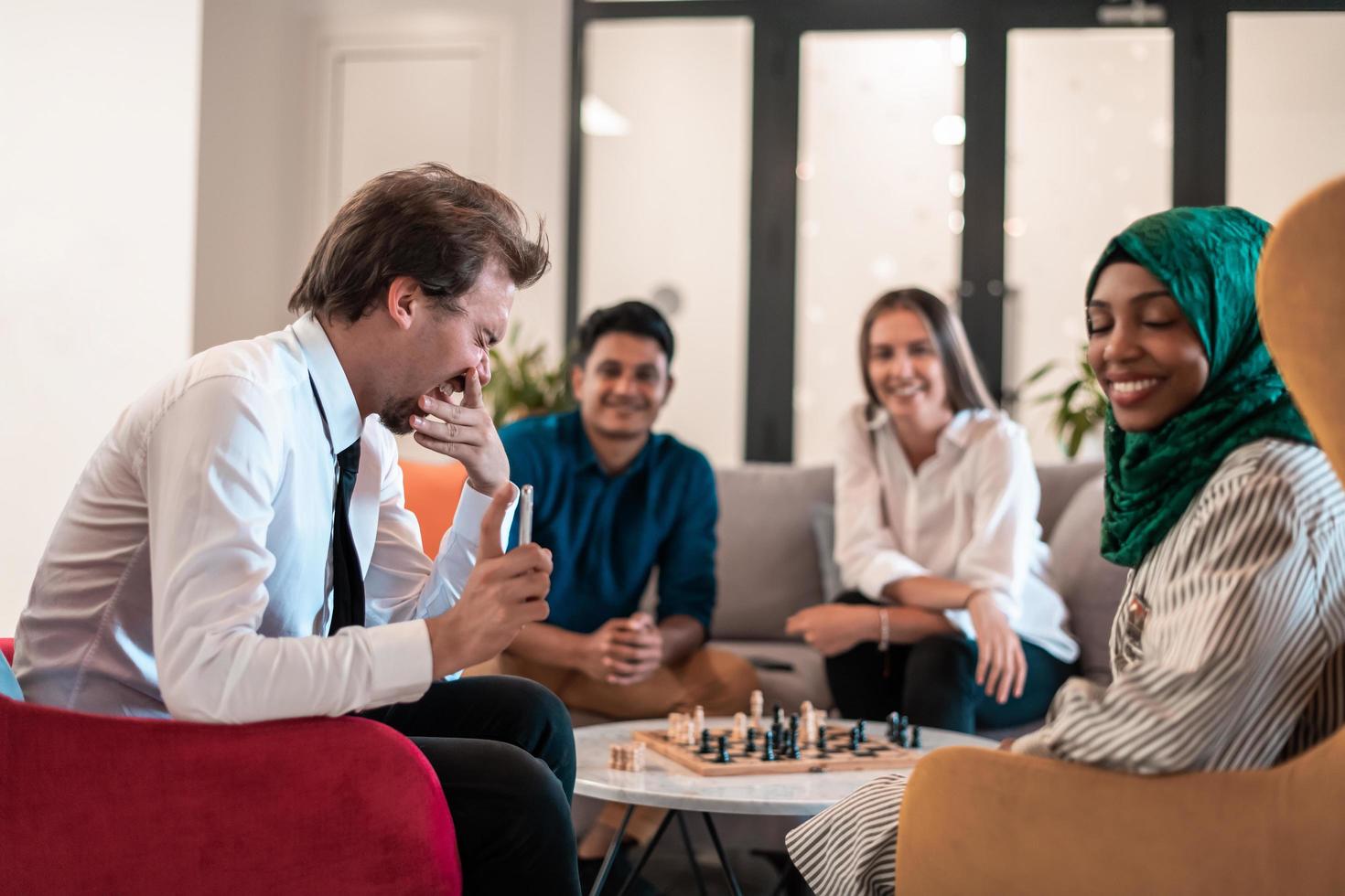 grupo multiétnico de empresarios jugando al ajedrez mientras descansan en el área de relajación en la moderna oficina de inicio. foto