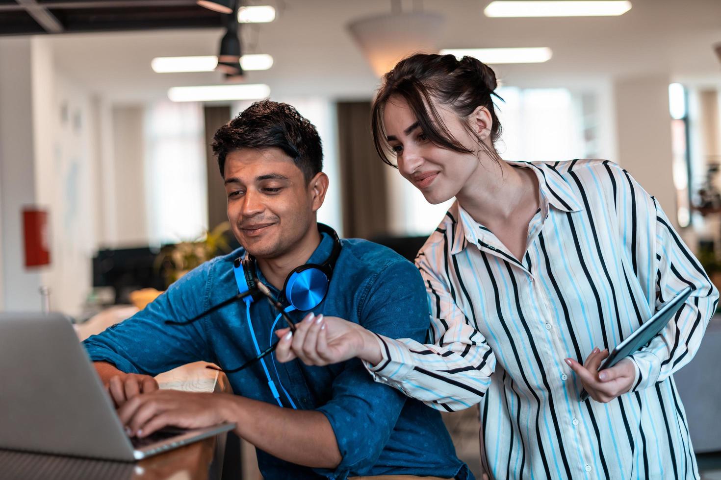 Multiethnic business people man with a female colleague working together on tablet and laptop computer in relaxation area of modern startup office photo