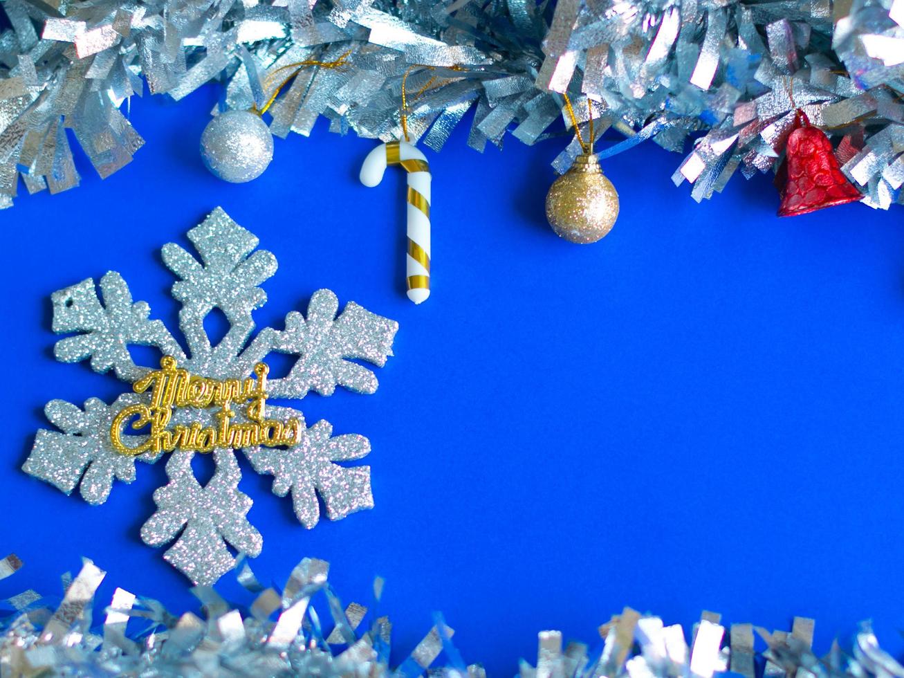 fondo de navidad, bolas decorativas y baratijas sobre fondo azul con texto de feliz navidad en copo de nieve brillante. foto