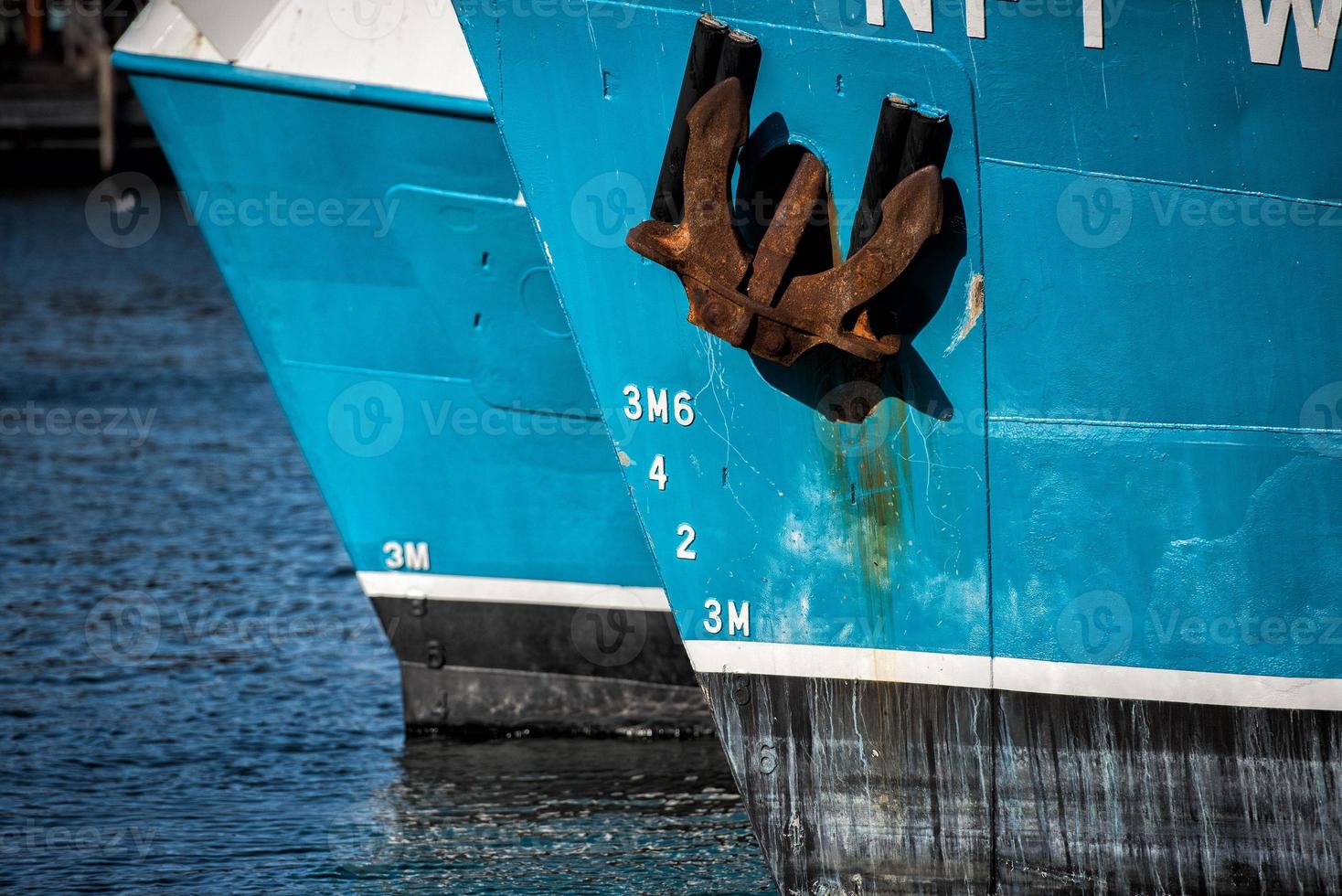 Rusted rugged Anchor on blue fishing ship photo