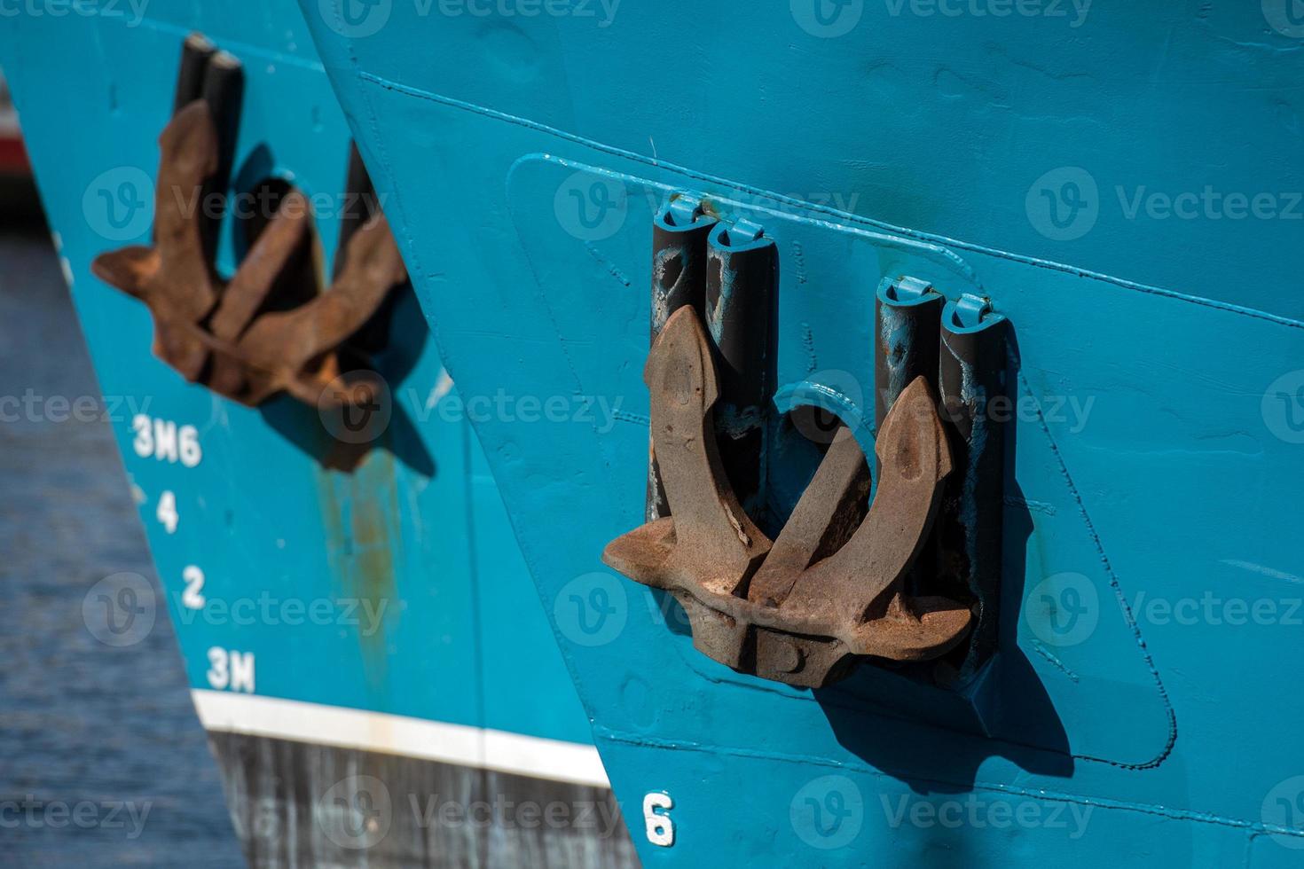 Rusted rugged Anchor on blue fishing ship photo