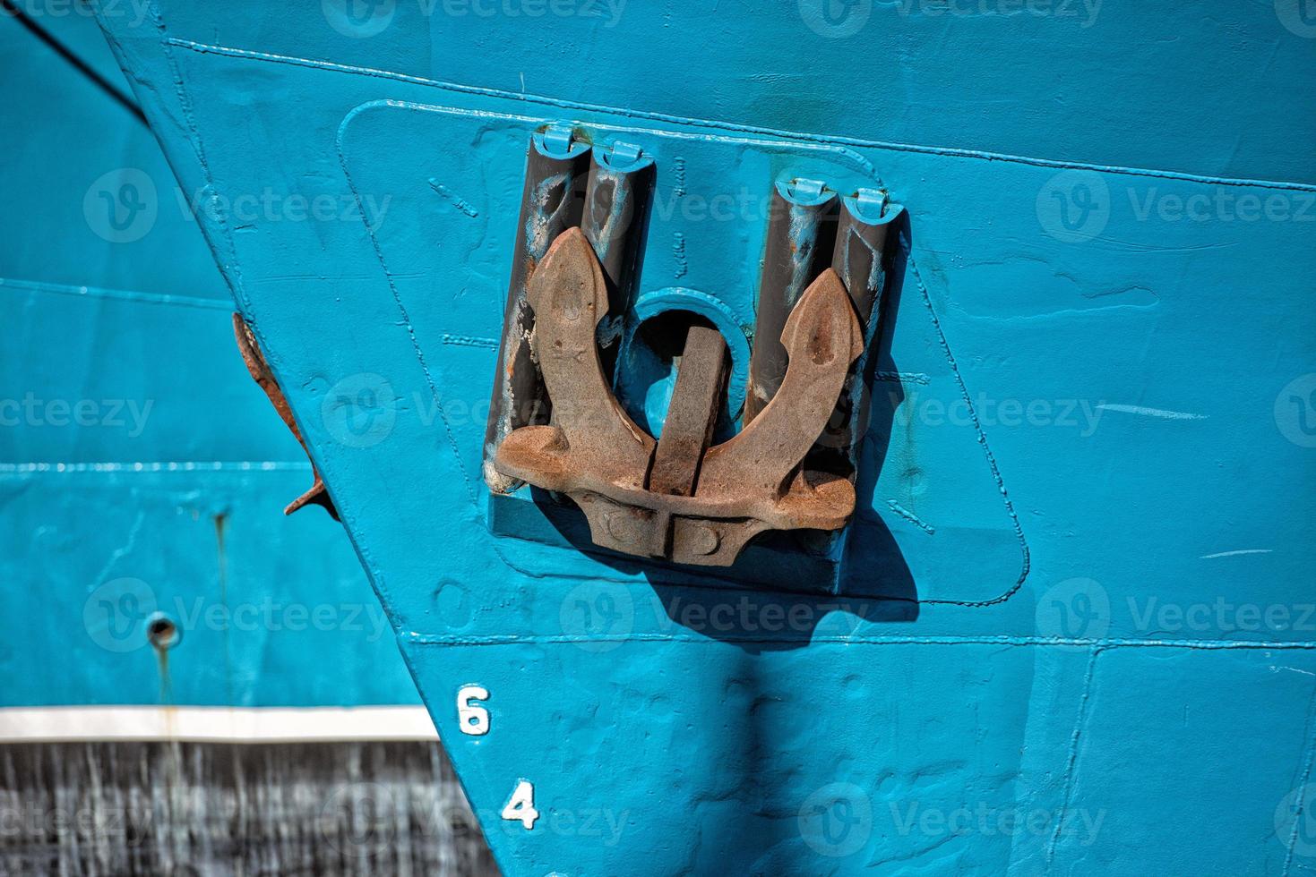 Rusted rugged Anchor on blue fishing ship photo