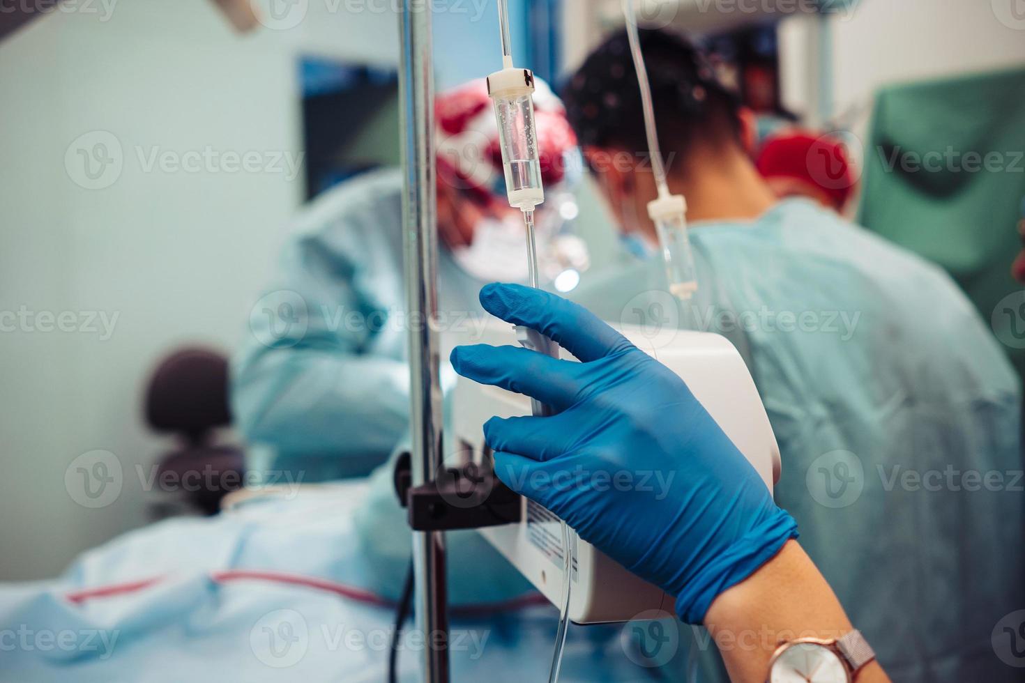 Nurse sets the patient's dropper on the background operation photo