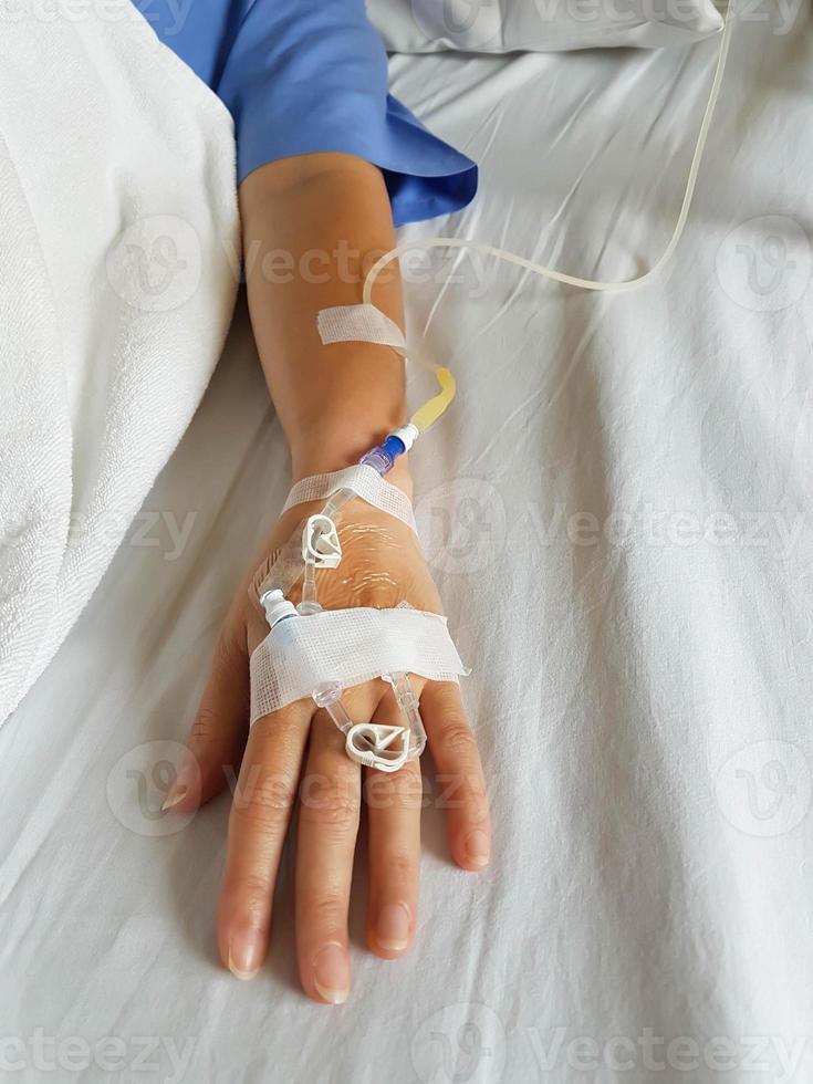 mano del paciente con aguja de infusión cuentagotas y tubo intravenoso. foto