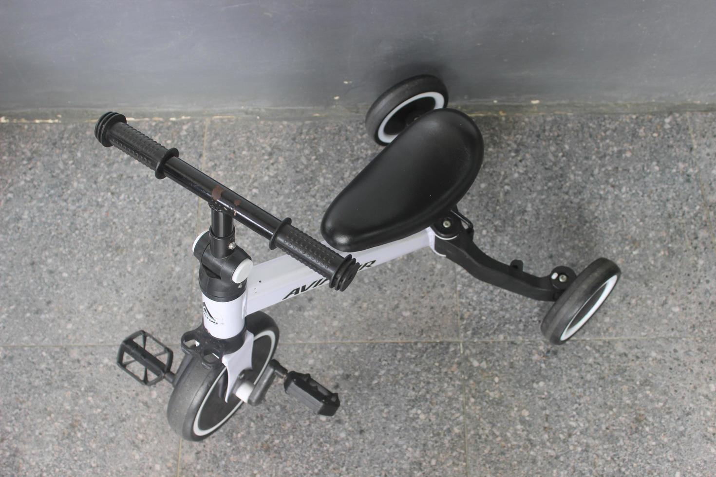 Children's tricycle in white and black color outdoors. photo