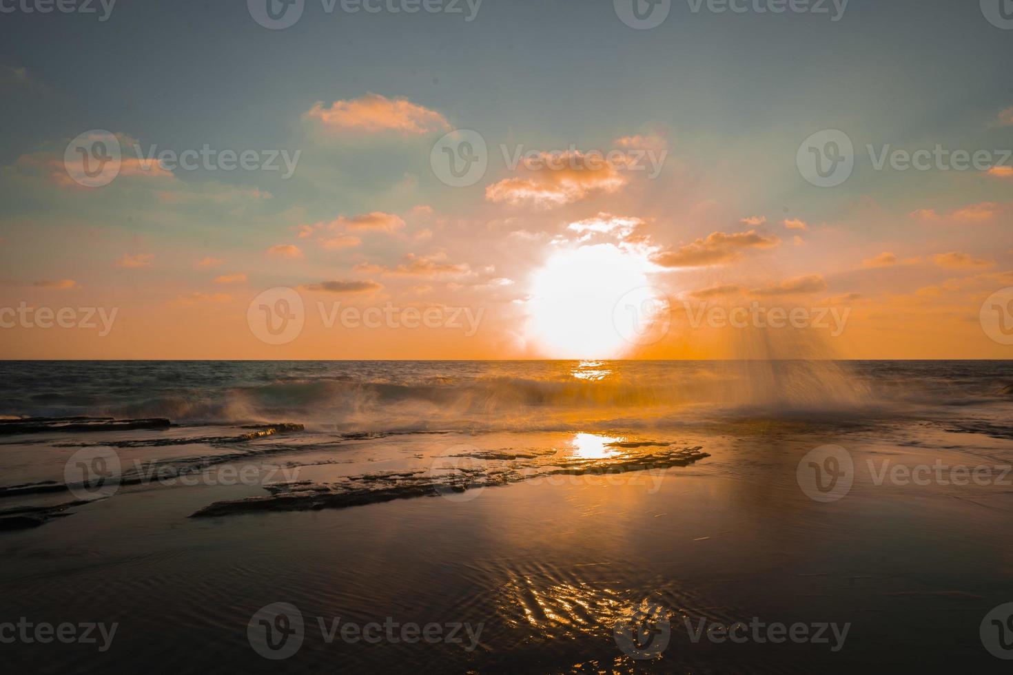 fotografía de larga exposición de olas y guijarros en la playa al atardecer foto