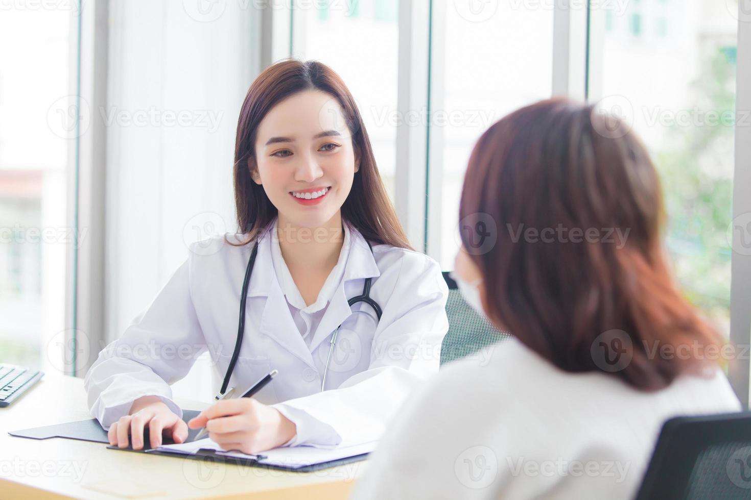 Asian professional doctor woman who wears medical coat talks with female patient to suggest treatment guideline and healthcare concept in office of hospital. photo