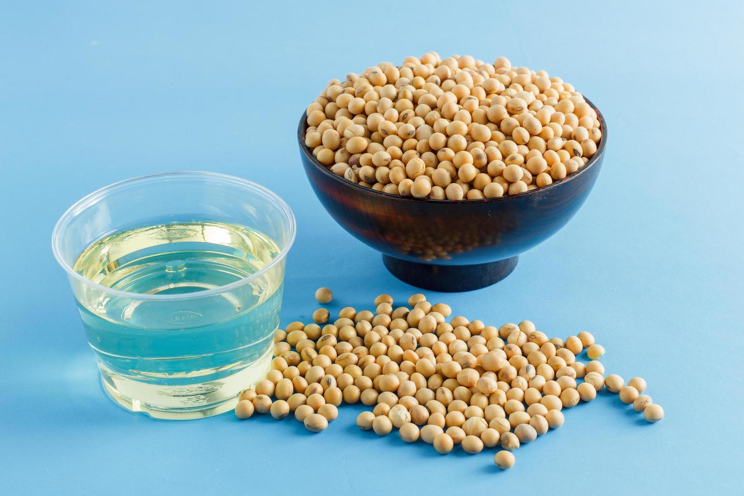 soybean and oil in a bowl on blue background, selective focus.copy space.front view. photo