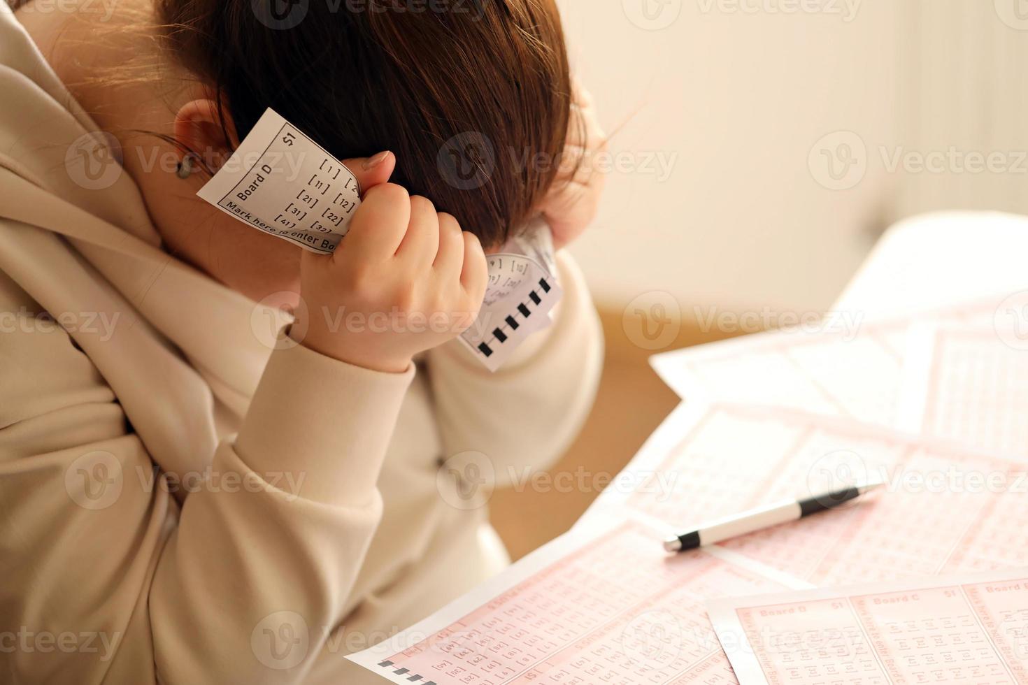 A sad young girl suffers from a loss after looking the unlucky result of the lottery gambling. The concept of losing the lottery and spend money photo