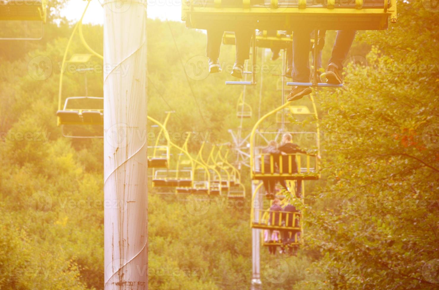 People ride on a cable car. The legs of passengers hang over the mountain forest photo