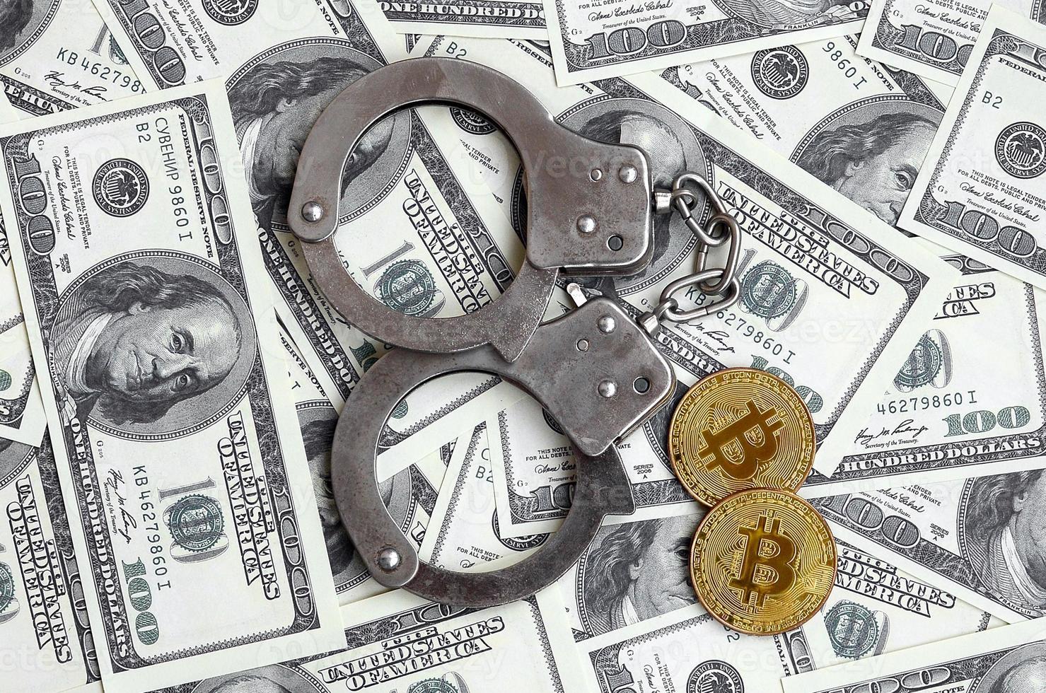 Police handcuffs and bitcoins lie on a large number of dollar bills. The concept of problems with the law during the illegal cryptocurrency mining and bitcoin operations photo
