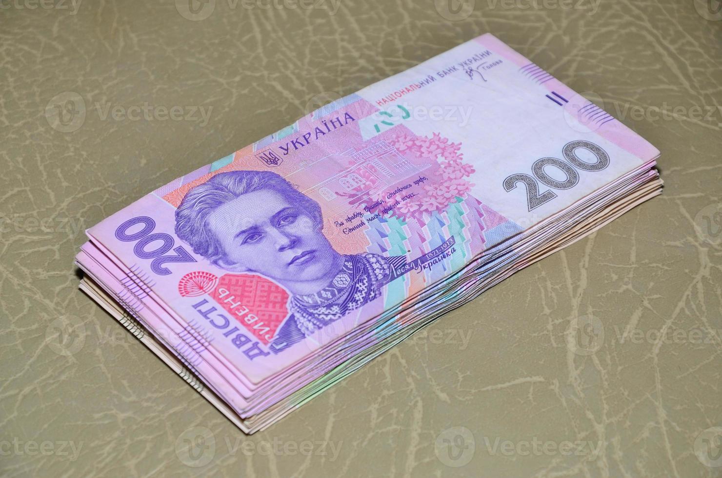 A close-up photograph of a set of Ukrainian money with a face value of 200 hryvnia, lying on a brown leather surface. Background image on business in Ukraine photo
