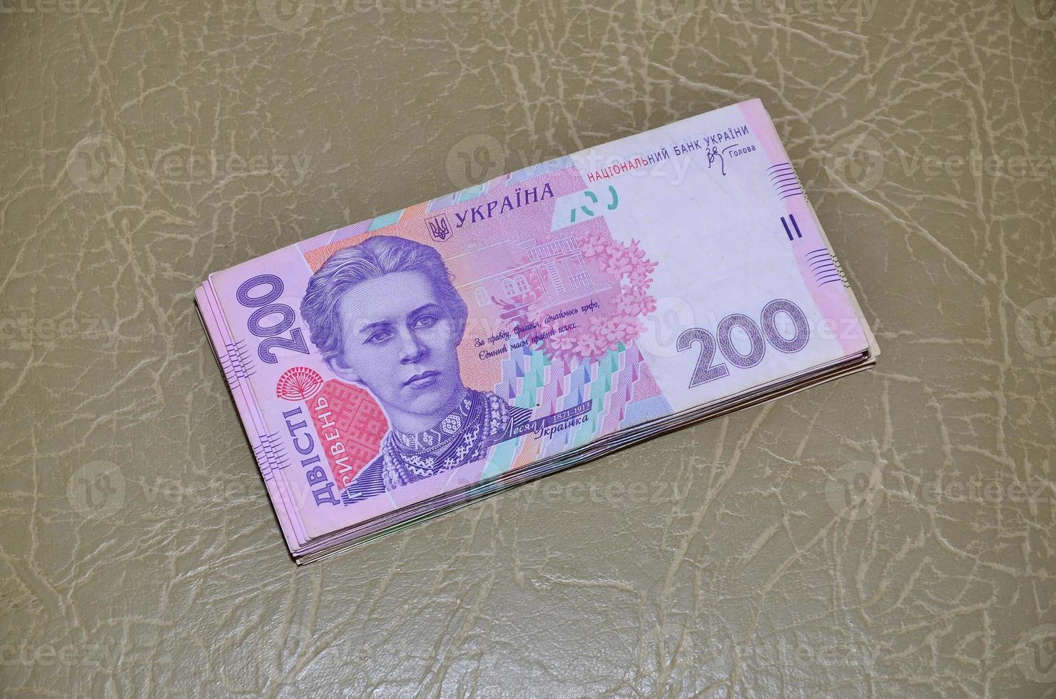 A close-up photograph of a set of Ukrainian money with a face value of 200 hryvnia, lying on a brown leather surface. Background image on business in Ukraine photo