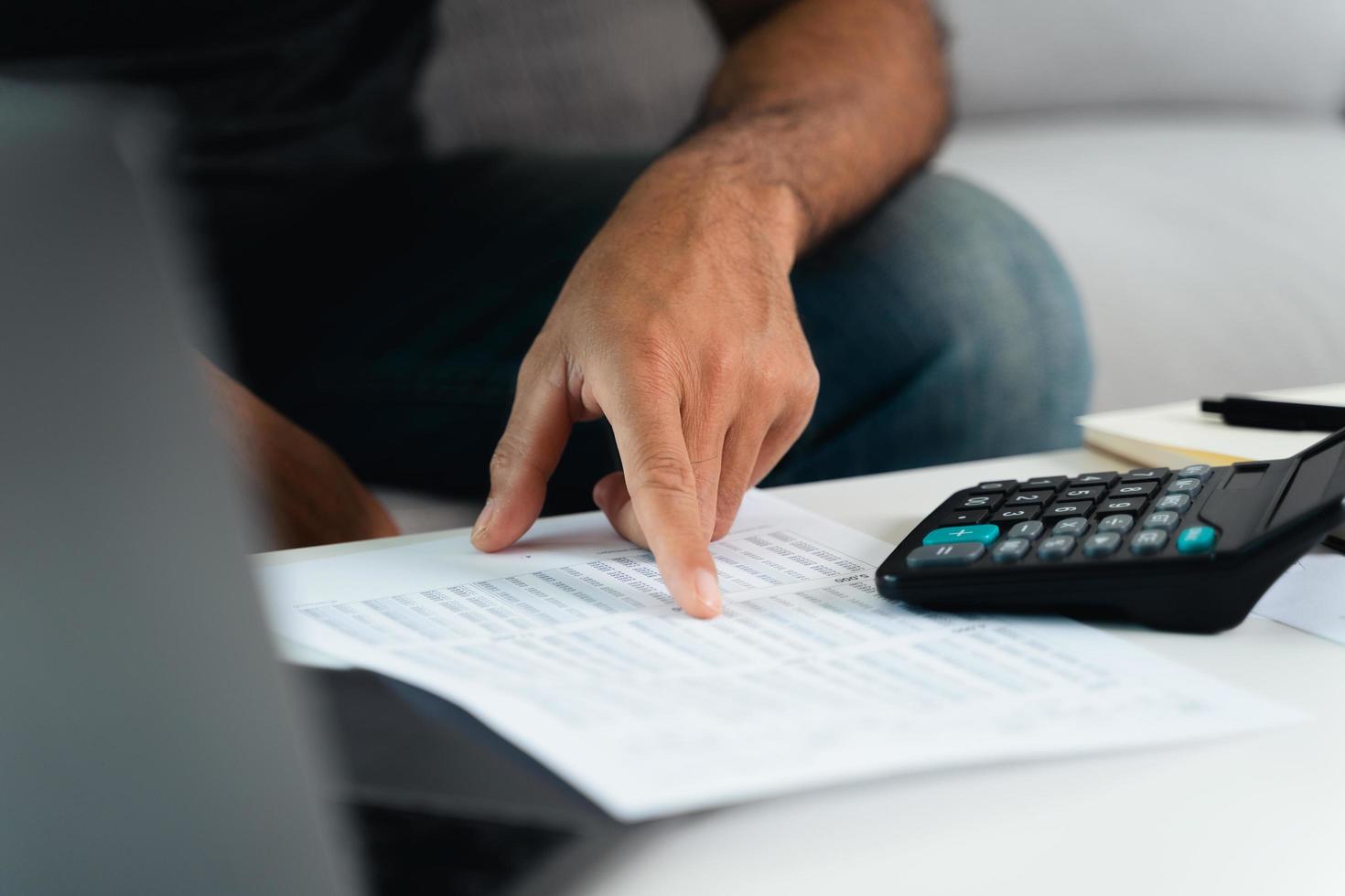 el hombre está calculando el impuesto anual con calculadora y llenando el formulario de declaración de impuestos sobre la renta individual. temporada para pagar impuestos y concepto de planificación presupuestaria. foto