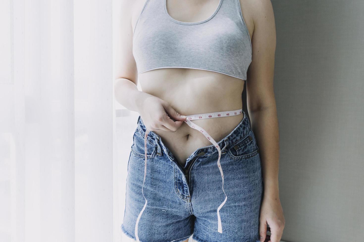 Beautiful fat woman with tape measure She uses her hand to squeeze the excess fat that is isolated on a white background. She wants to lose weight, the concept of surgery and break down fat under the photo