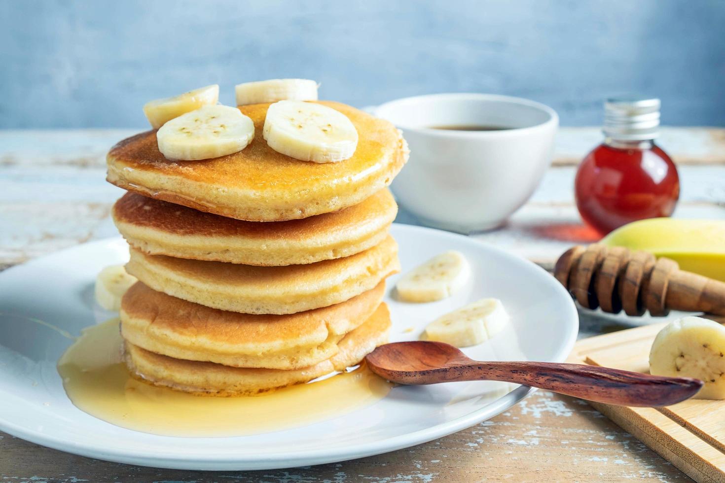 pila de panqueques de plátano con rodajas de plátanos frescos, una pila de panqueques caseros dulces con mantequilla y jarabe para el desayuno en un fondo de madera foto