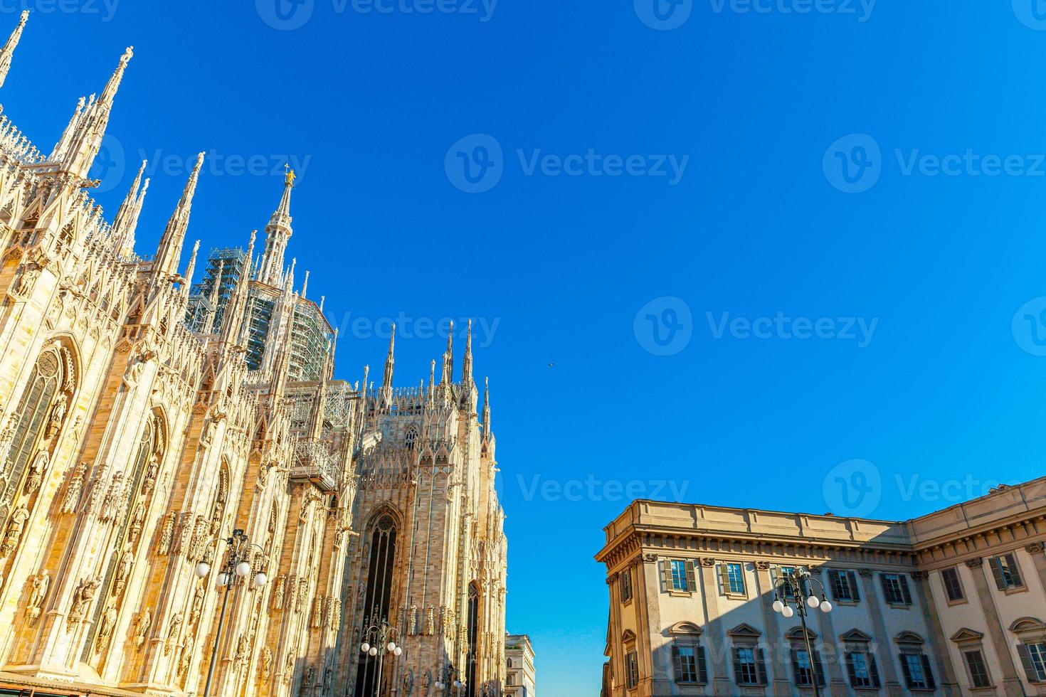 Famous church Milan Cathedral Duomo di Milano with Gothic spires and white marble statues. Top tourist attraction on piazza in Milan Lombardia Italy. Wide angle view of old Gothic architecture and art photo