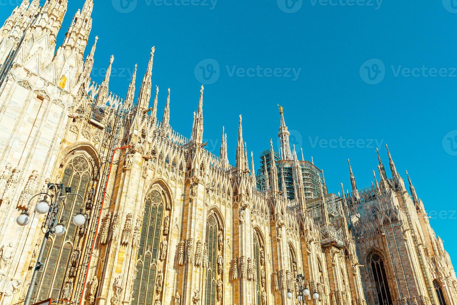 Famous church Milan Cathedral Duomo di Milano with Gothic spires and white marble statues. Top tourist attraction on piazza in Milan Lombardia Italy. Wide angle view of old Gothic architecture and art photo